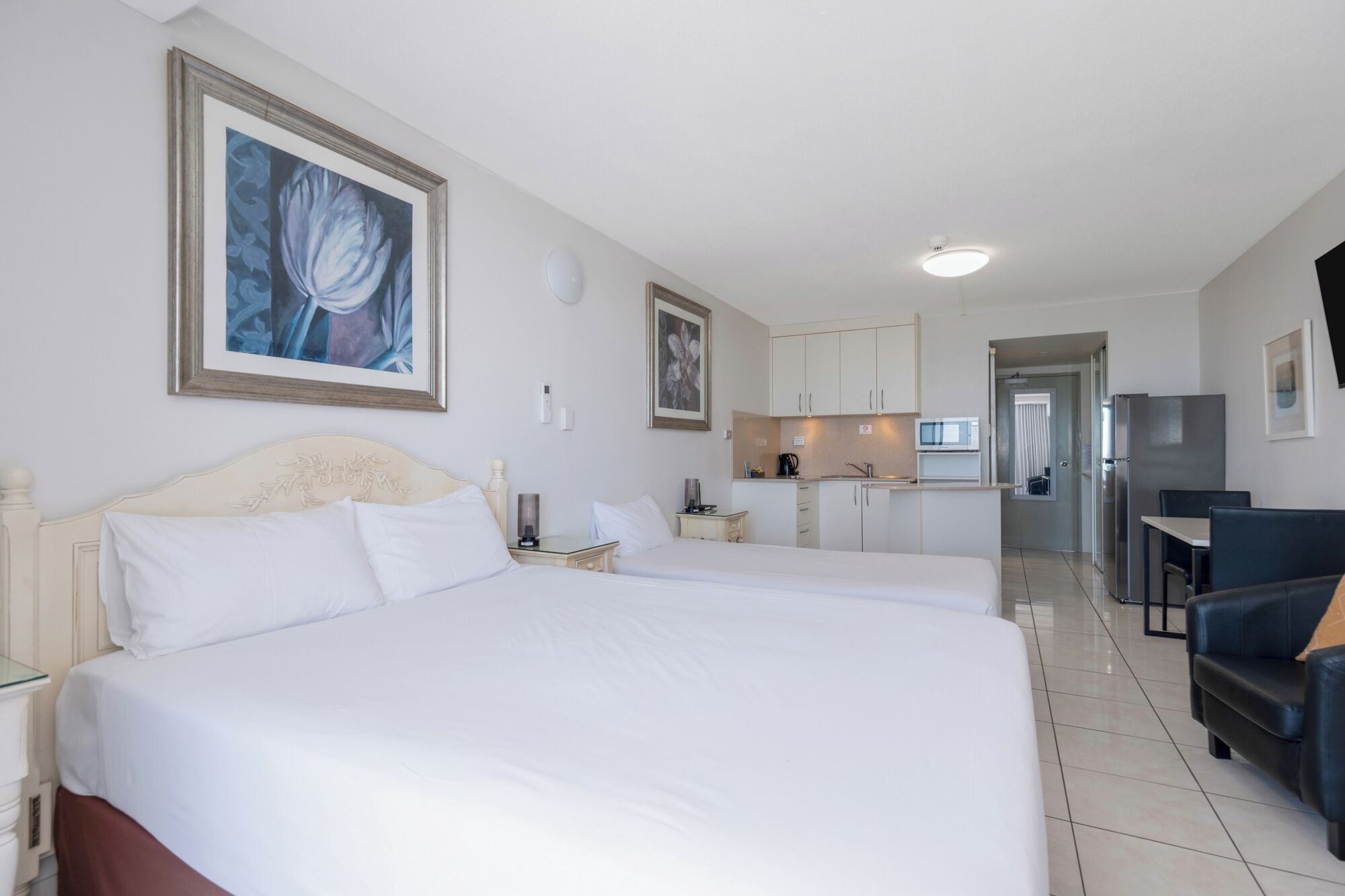 Hotellihuone, jossa on suuri sänky, pieni keittiö, ruokailutila ja kylpyhuone.