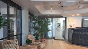 Un hall d’entrée avec des meubles en osier, des plantes en pot et un comptoir d’accueil.