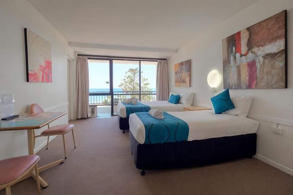 Habitación de hotel con cama, escritorio, silla y vistas al exterior.