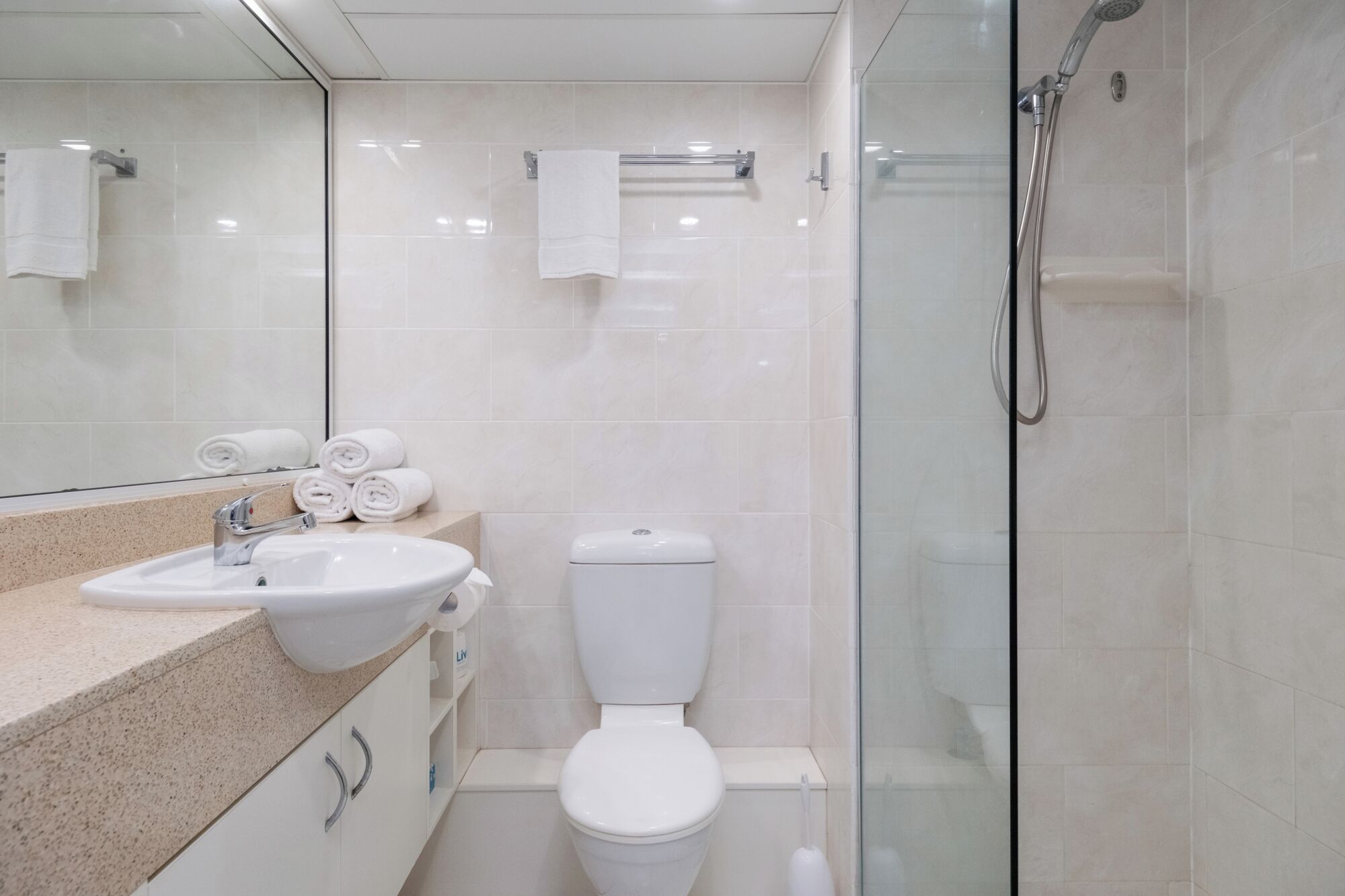 A modern bathroom with a glass-enclosed shower, a white sink, and a toilet.