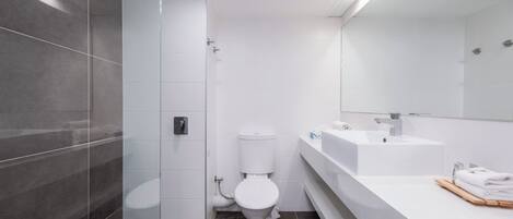 Un baño moderno con inodoro, lavamanos y cabina de ducha.