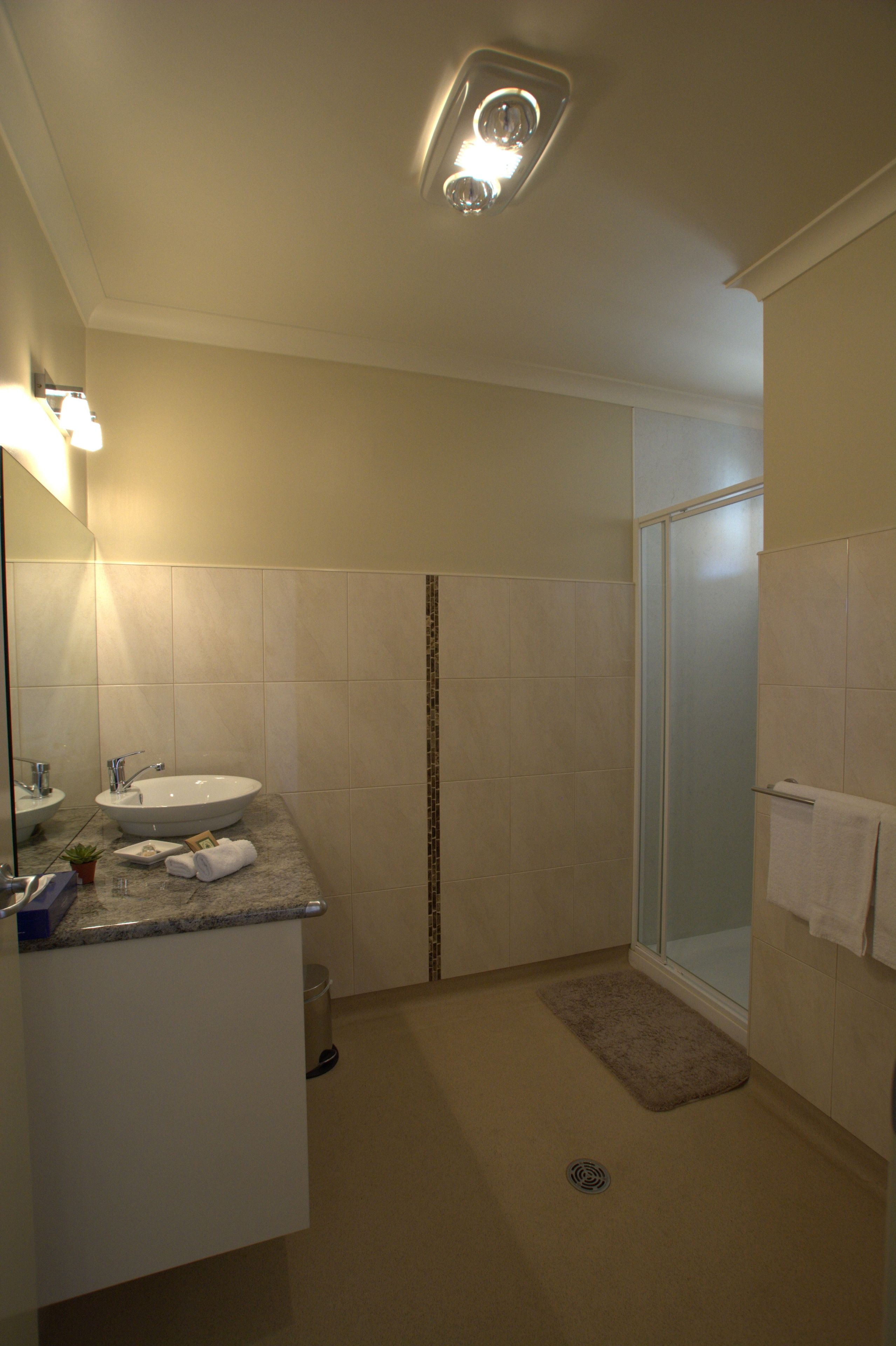 Une salle de bain équipée d’un lavabo, d’un miroir, d’un porte-serviettes et d’une douche.