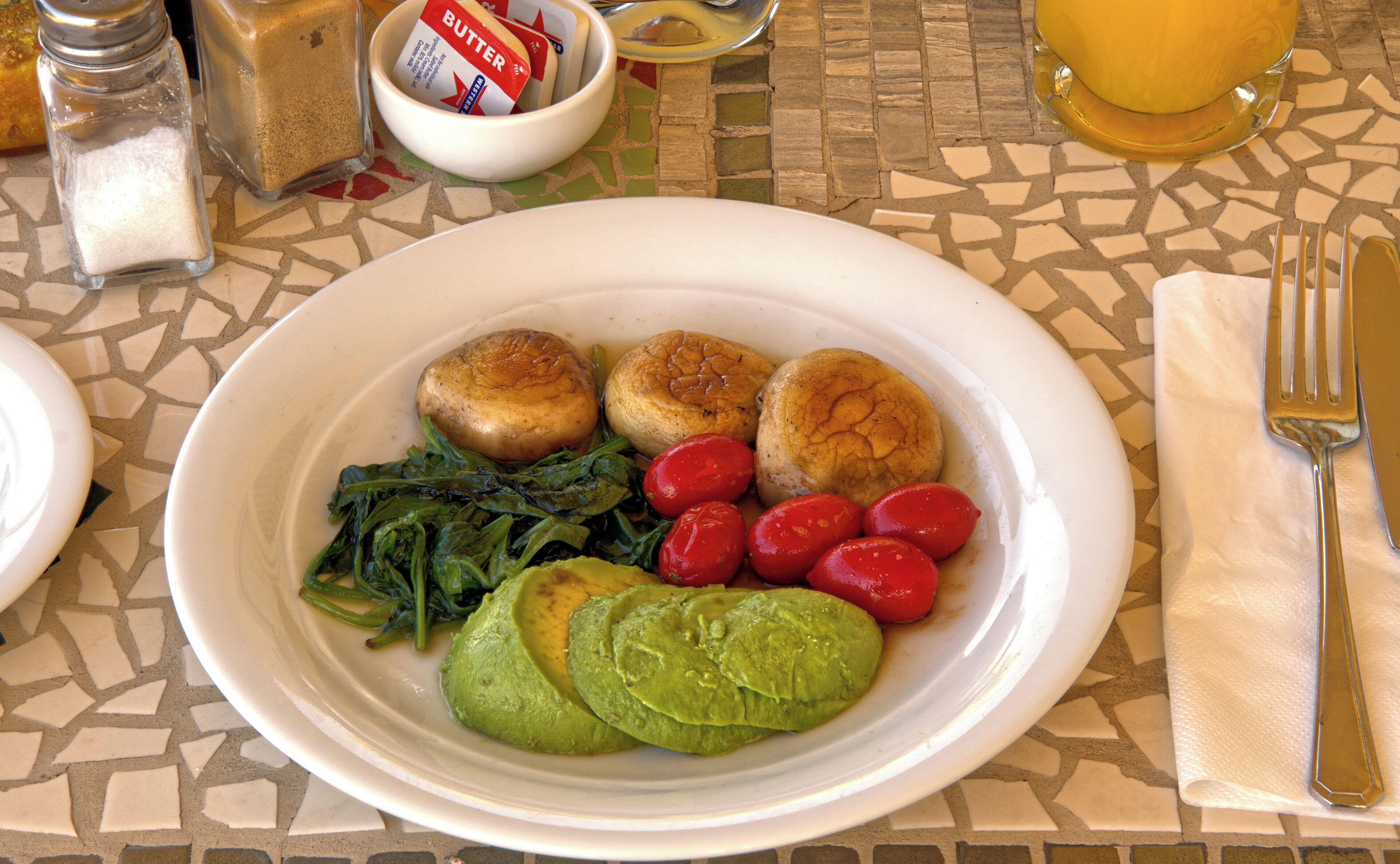 A plate with food items including potatoes, greens, and tomatoes.