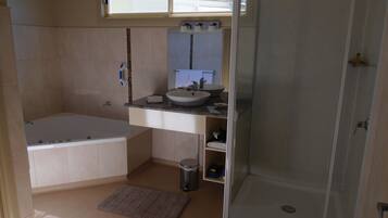 A bathroom with a bathtub, a sink, a mirror, and a shower.
