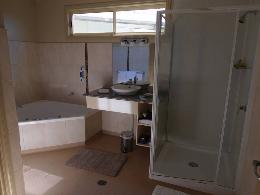 A bathroom with a bathtub, a sink, a mirror, and a shower.