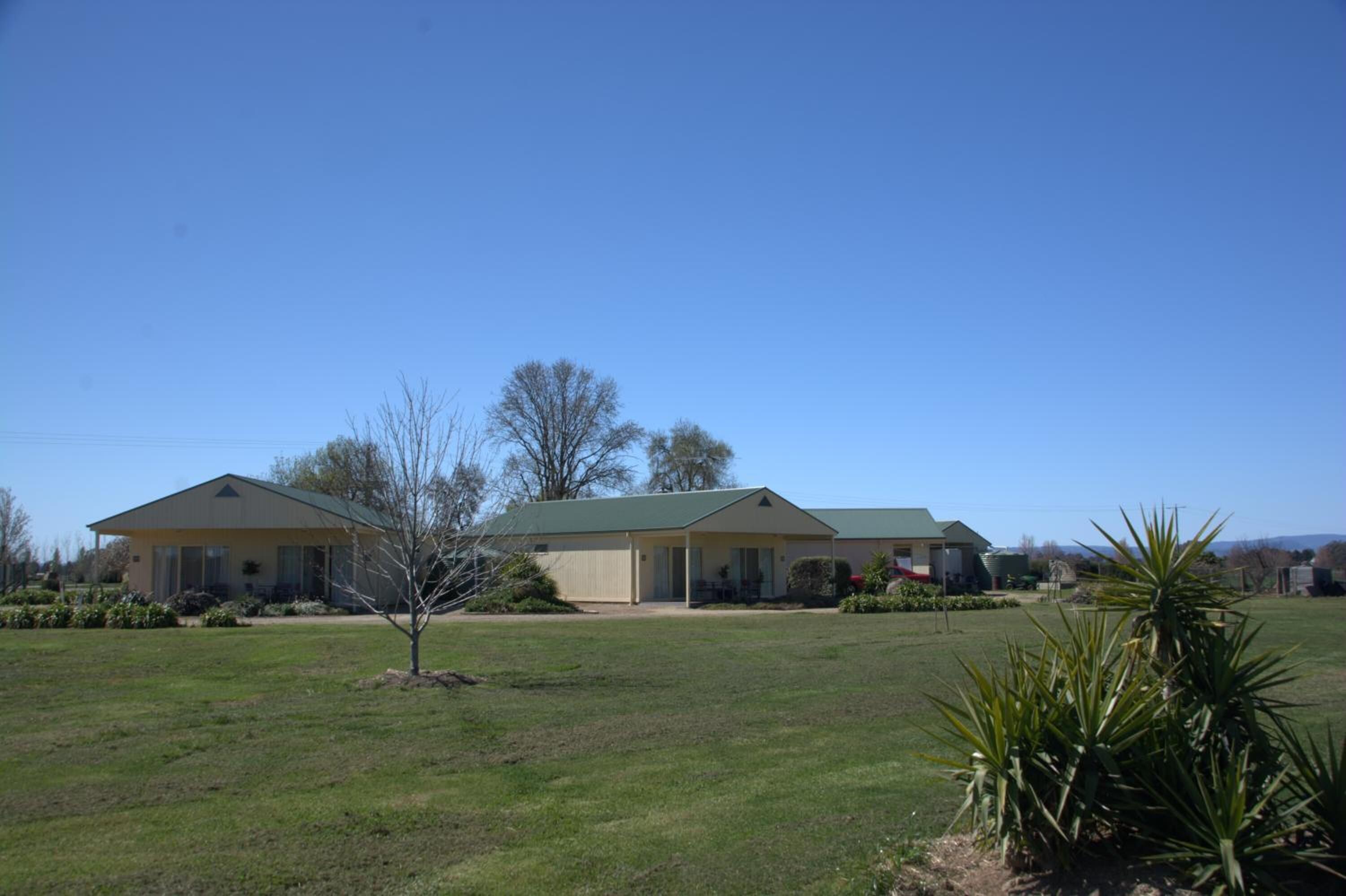 A two-story building with a green roof, surrounded by a grassy lawn and a few trees.