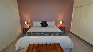 A bedroom with a bed, bedside tables, a bench, and a wardrobe.