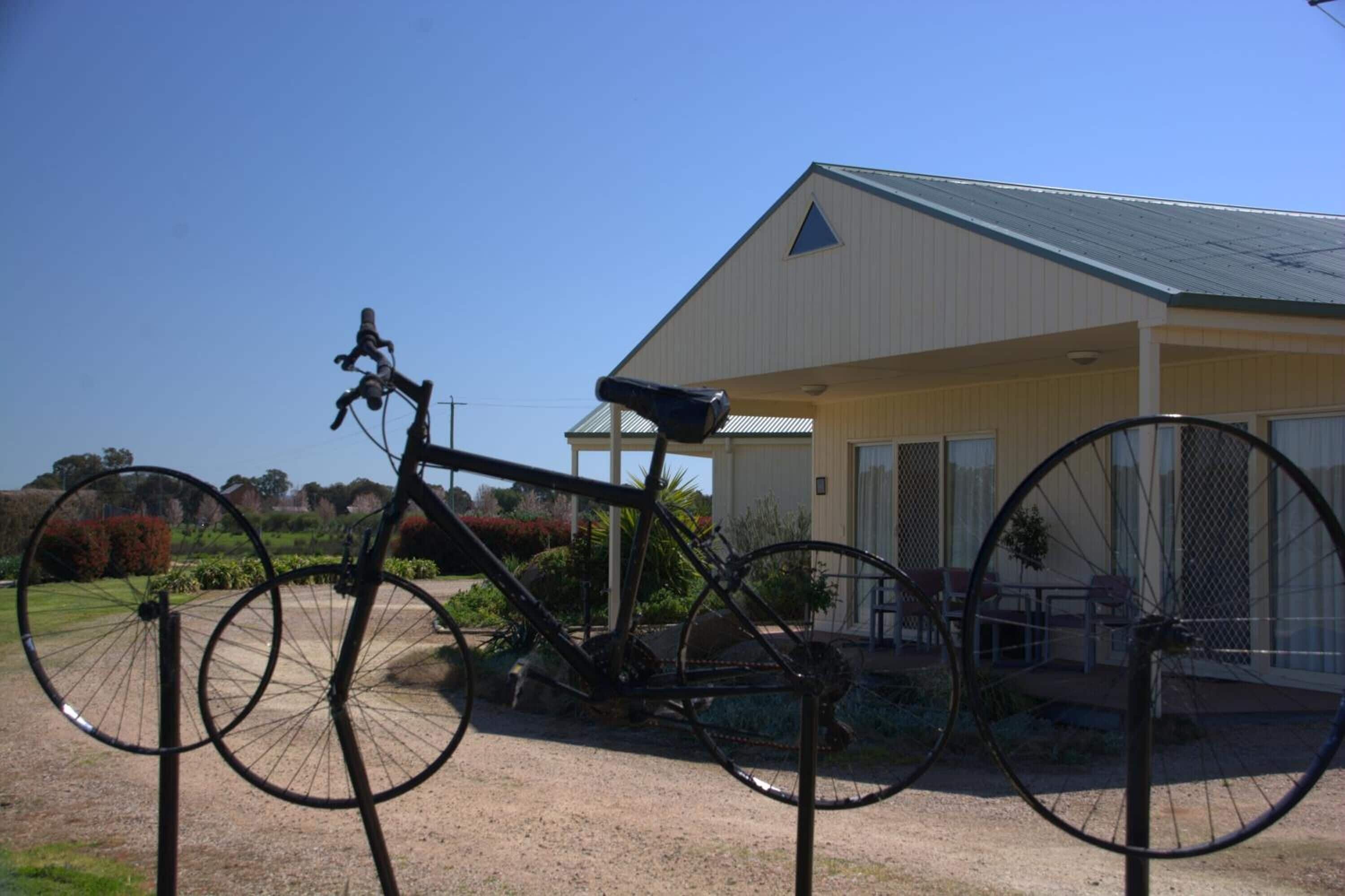 A bicycle parked in front of a building with a triangular roof and a covered patio area.