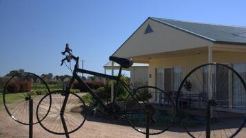 A bicycle parked in front of a building with a triangular roof and a covered patio area.