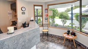 A reception area with a marble counter, a clock, and a window offering a view of the outdoors. - Bonnie Knights Motel (Mosgiel)
