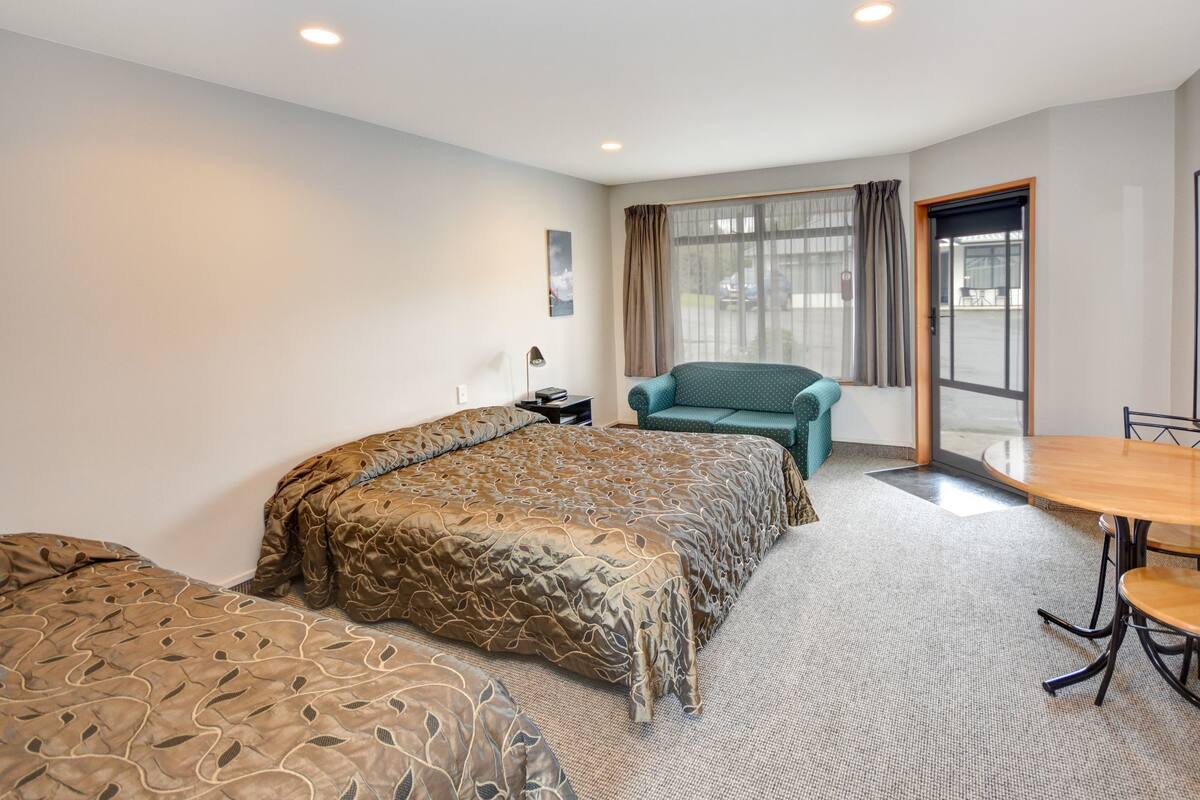 A hotel room with a bed, a desk, a chair, and a window with curtains.