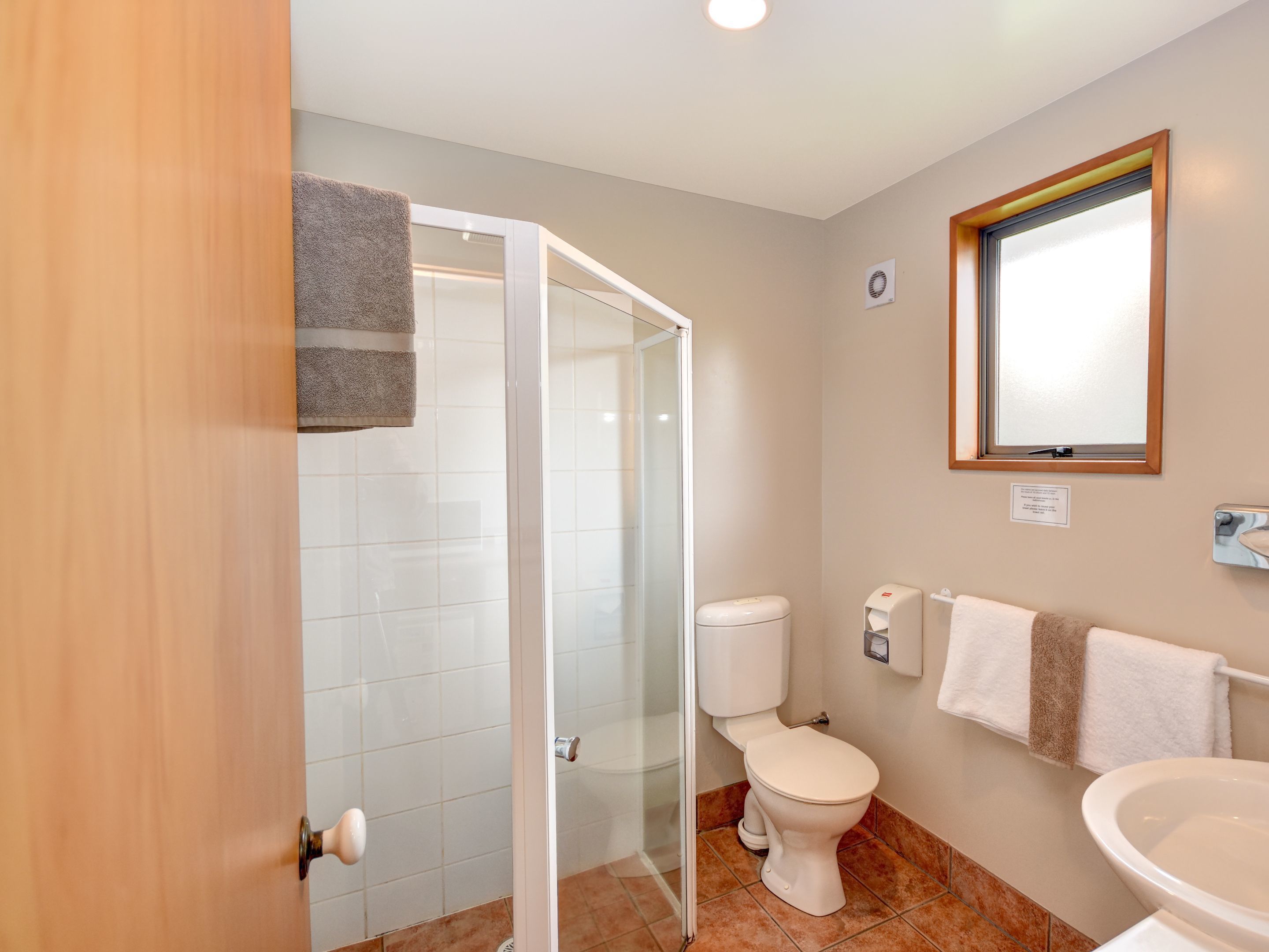 Ein Badezimmer mit Duschkabine, Toilette, Waschbecken und Fenster.