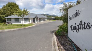 A building with a sign reading "Bonnie Knights" and a picnic table in the foreground. - Bonnie Knights Motel (Mosgiel)