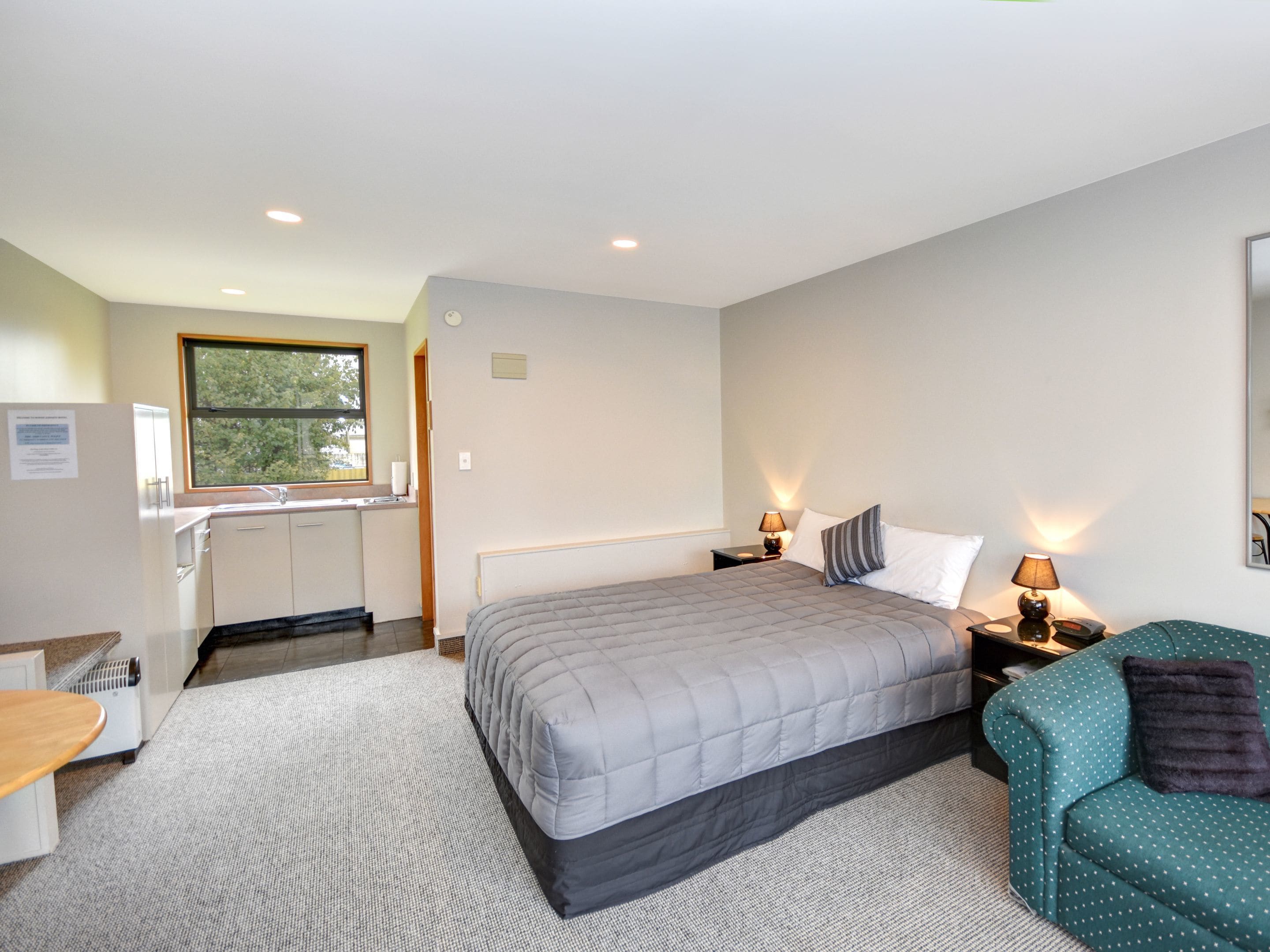 A bedroom with a bed, bedside tables, a desk, and a chair.