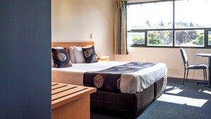 A hotel room with a bed, a wooden bench, a small table, and a chair. - Black Buffalo Hotel (North Hobart)