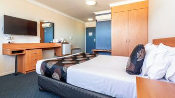 A hotel room with a bed, a desk, a television, and a wardrobe.