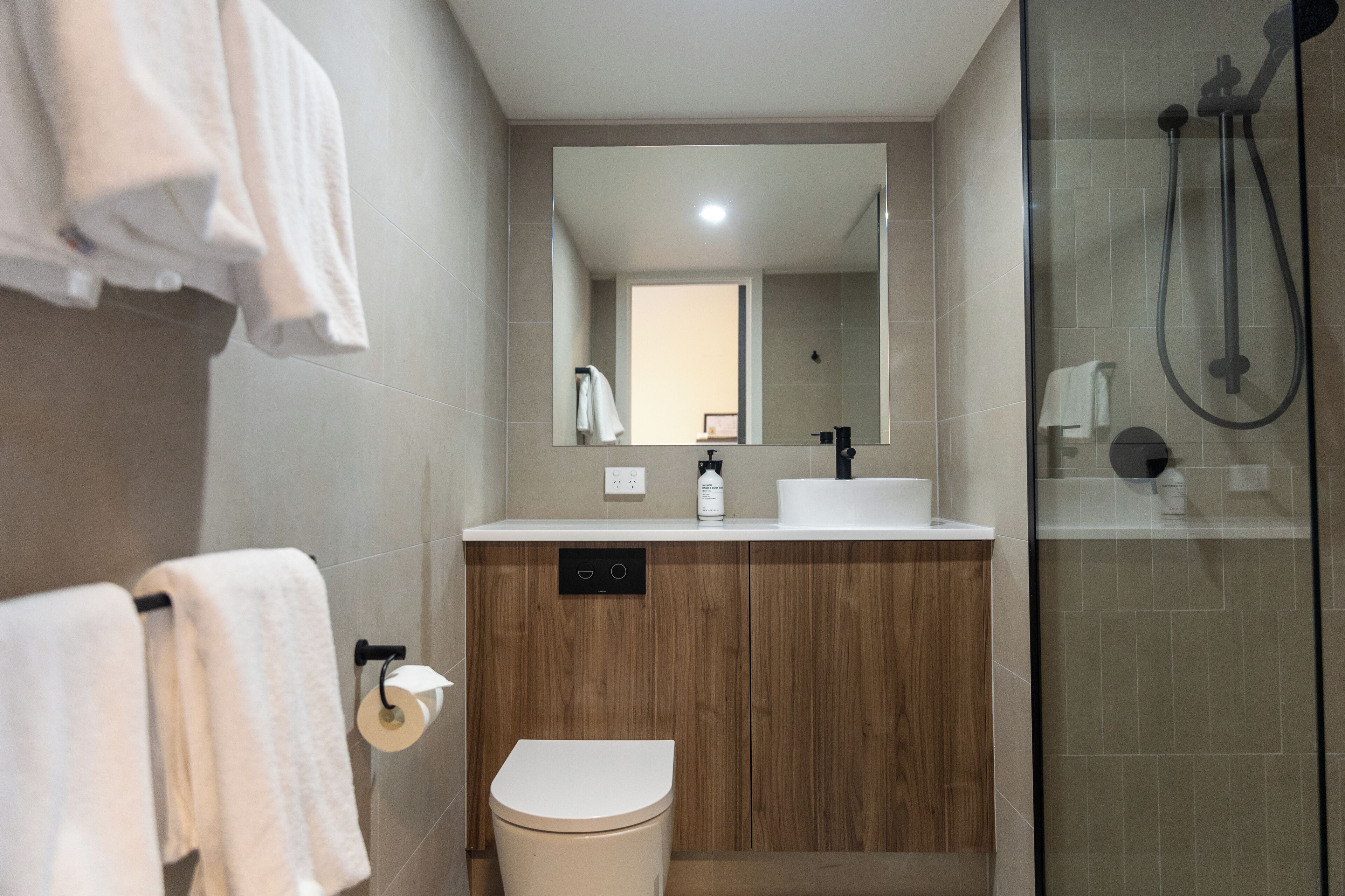 Un baño moderno con inodoro, lavamanos, espejo y ducha.