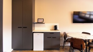A compact kitchenette with a refrigerator, a small countertop, and a TV mounted on the wall. - Black Buffalo Hotel (North Hobart)