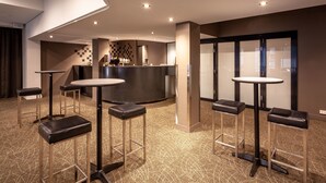 A modern hotel lobby with round tables and bar stools, a reception desk, and a patterned carpet. - Black Buffalo Hotel (North Hobart)
