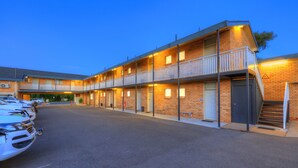 A motel with a two-story structure, a covered parking area, and a staircase leading to the upper floor.