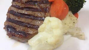 A plate with a grilled steak, carrots, broccoli, and cauliflower.