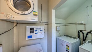 A laundry room with a front-loading washing machine, a lint filter, and a soap powder dispenser.