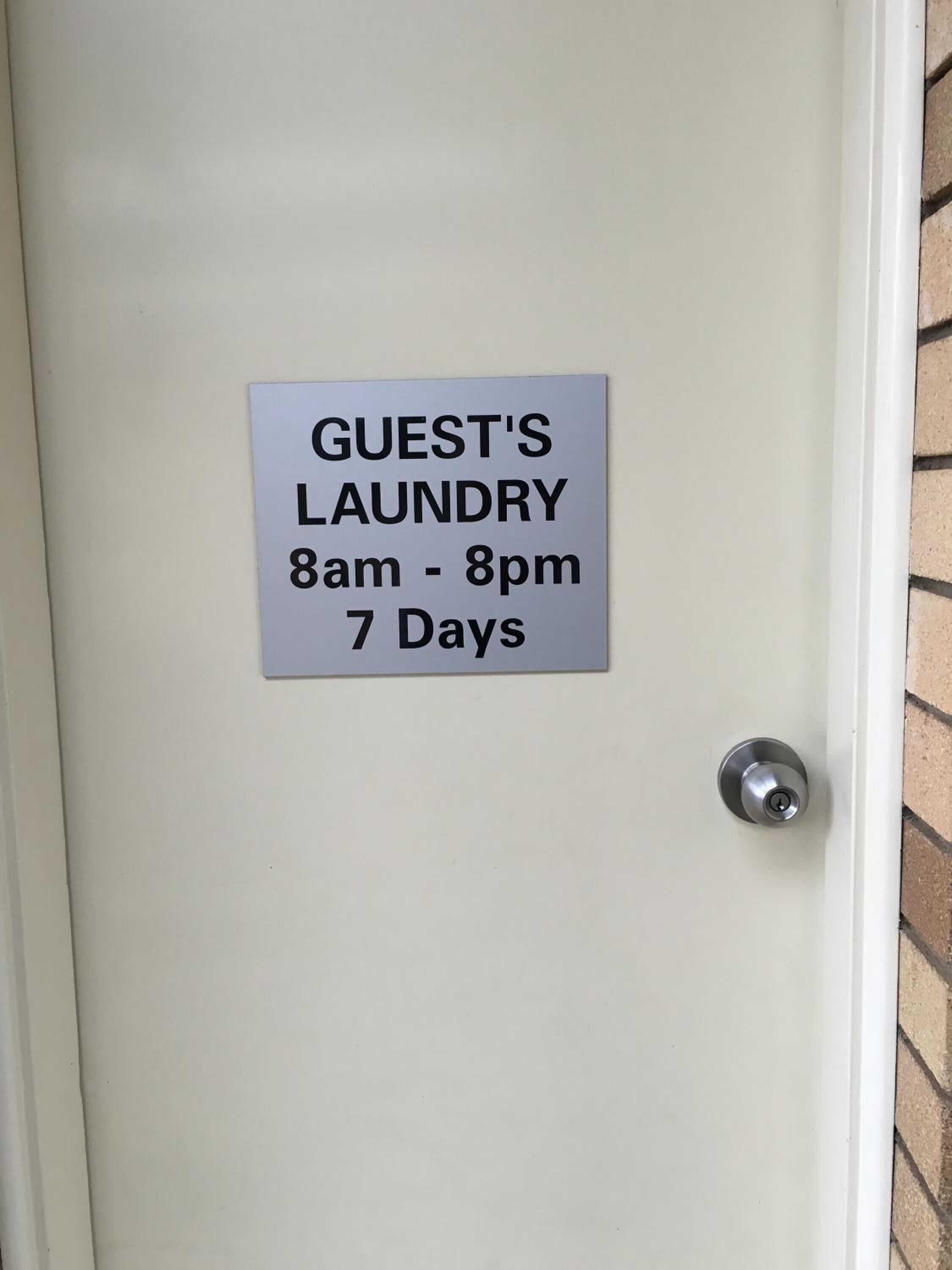 A door with a sign indicating guest's laundry hours from 8am to 8pm, available 7 days.