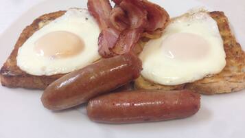A plate with two fried eggs, two strips of bacon, and two sausages.