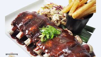 A plate of barbecued ribs with coleslaw and French fries.