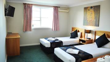 A hotel room with two single beds, a TV, a painting, and a window with curtains.