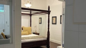 A modern bedroom with a four-poster bed, a hanging light fixture, and a large mirror. - CocknBull Boutique Hotel (Echuca)