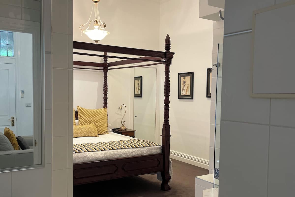 Un dormitorio moderno con cama con dosel, lámpara colgante y un espejo grande.