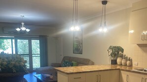 A modern kitchen with white cabinets, a granite countertop, and pendant lighting. - CocknBull Boutique Hotel (Echuca)