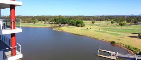 A view of a river with a dock and a golf course in the background.