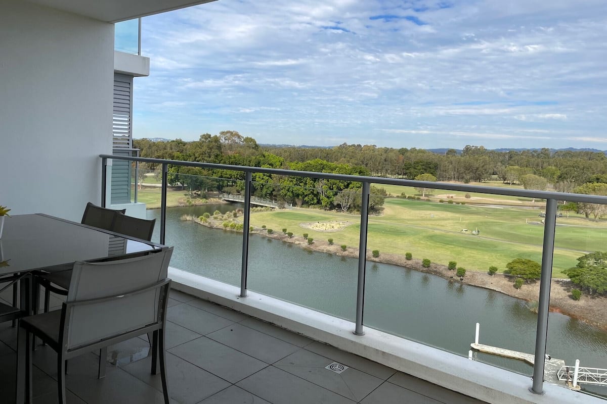 A balcony with a view of a golf course and a river.