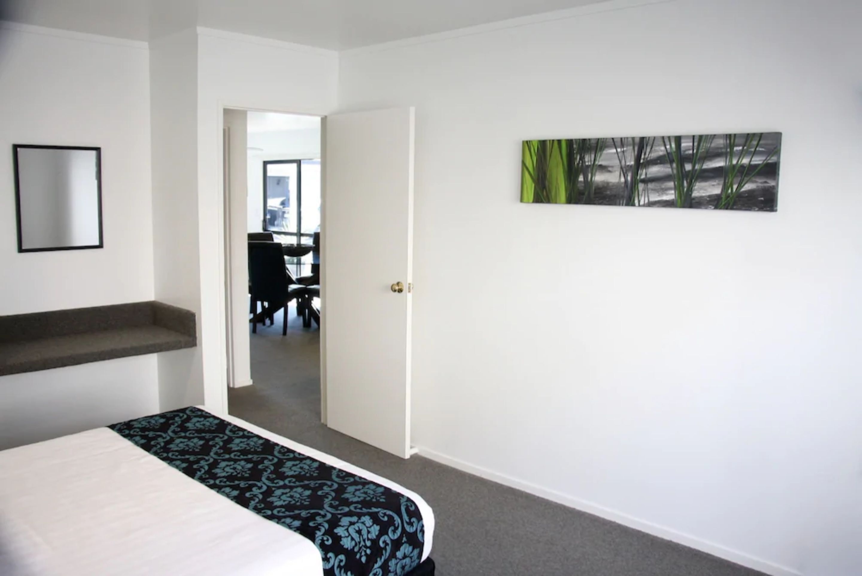 A hotel room with a bed, a desk, and a chair in the background.