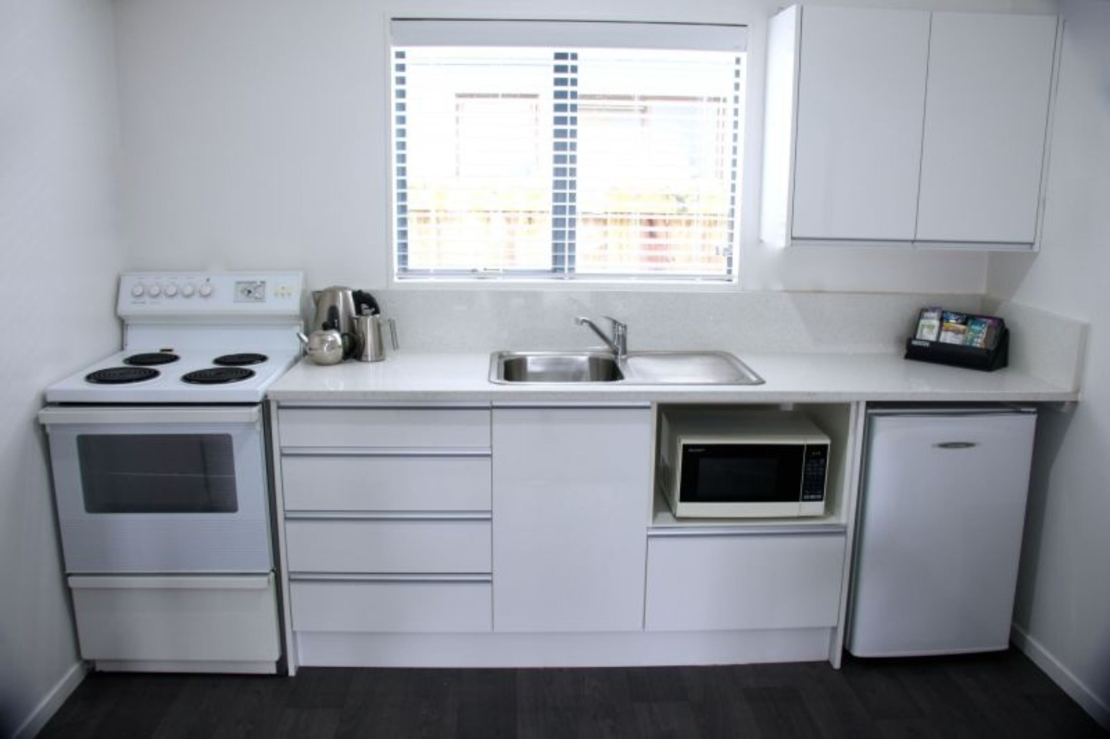 Una cocina compacta con estufa, fregadero, microondas y refrigerador.