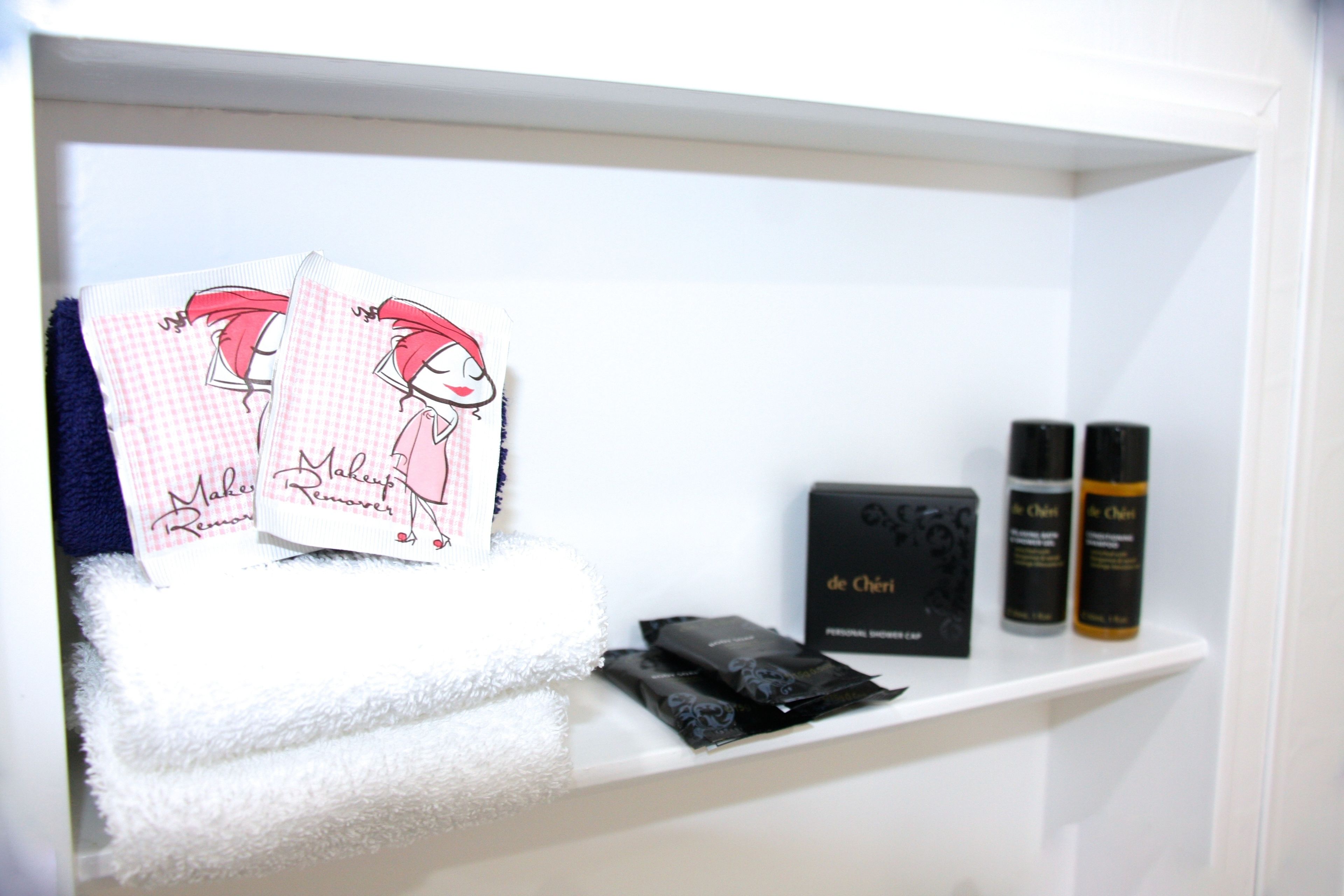 A shelf with makeup remover cards, a box labeled 'de Cheri', and two bottles of 'de Cheri' products.