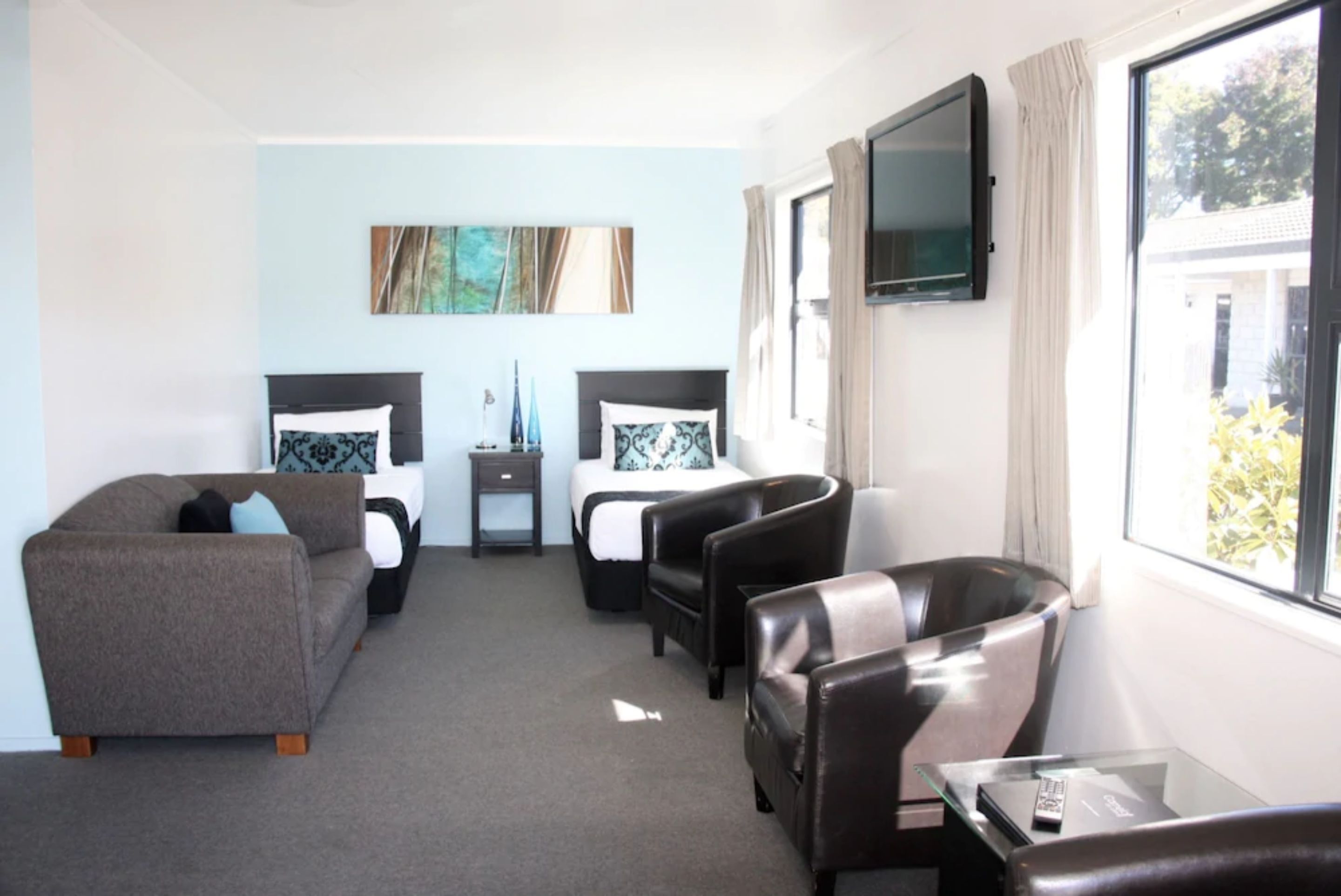 A hotel room with two beds, a sofa, a TV, and a window with a view.