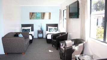 A hotel room with two beds, a sofa, a TV, and a window with a view.