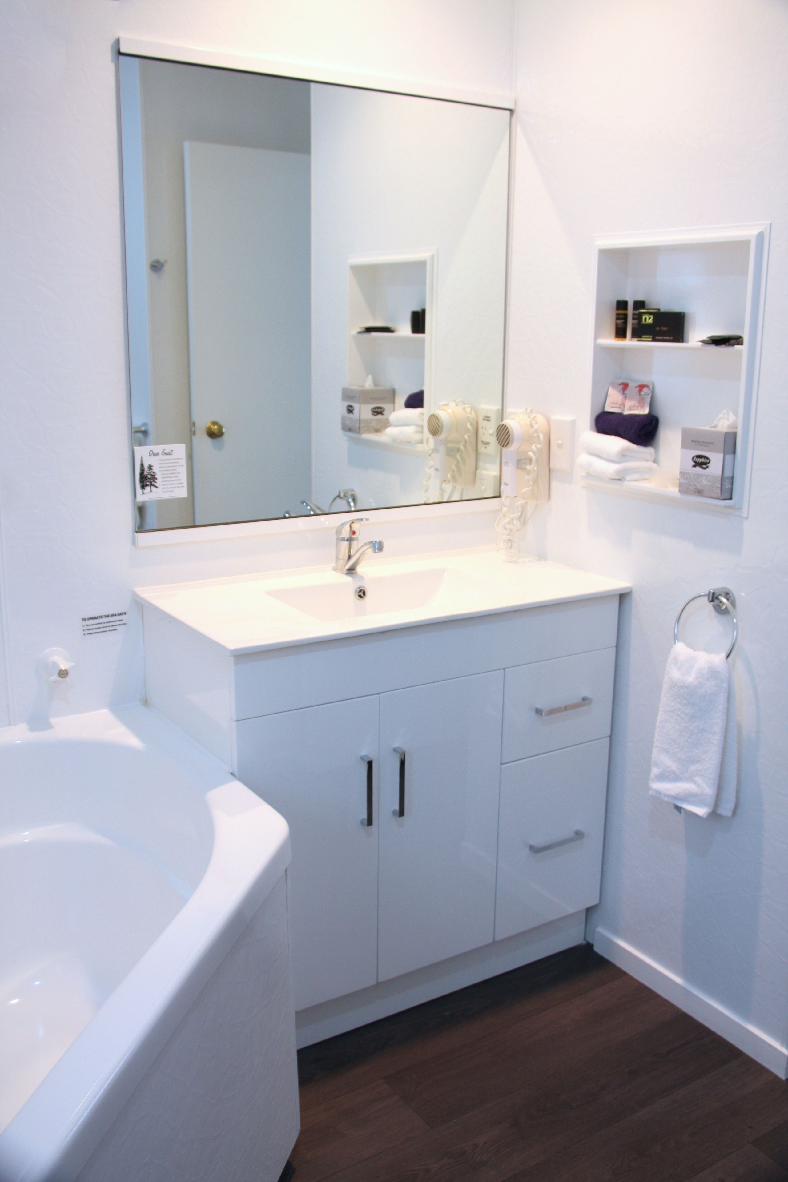 A modern bathroom with a white sink, vanity, and bathtub.