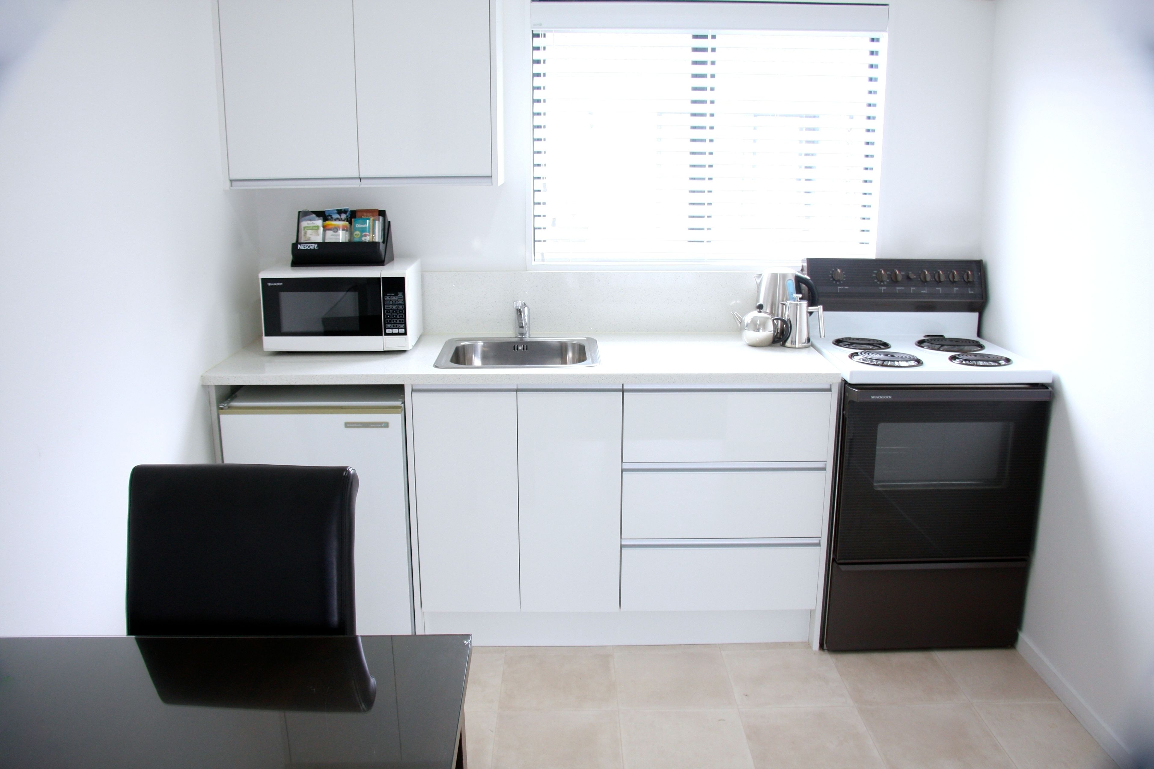 A compact kitchen with a microwave, sink, stove, and a dishwasher.