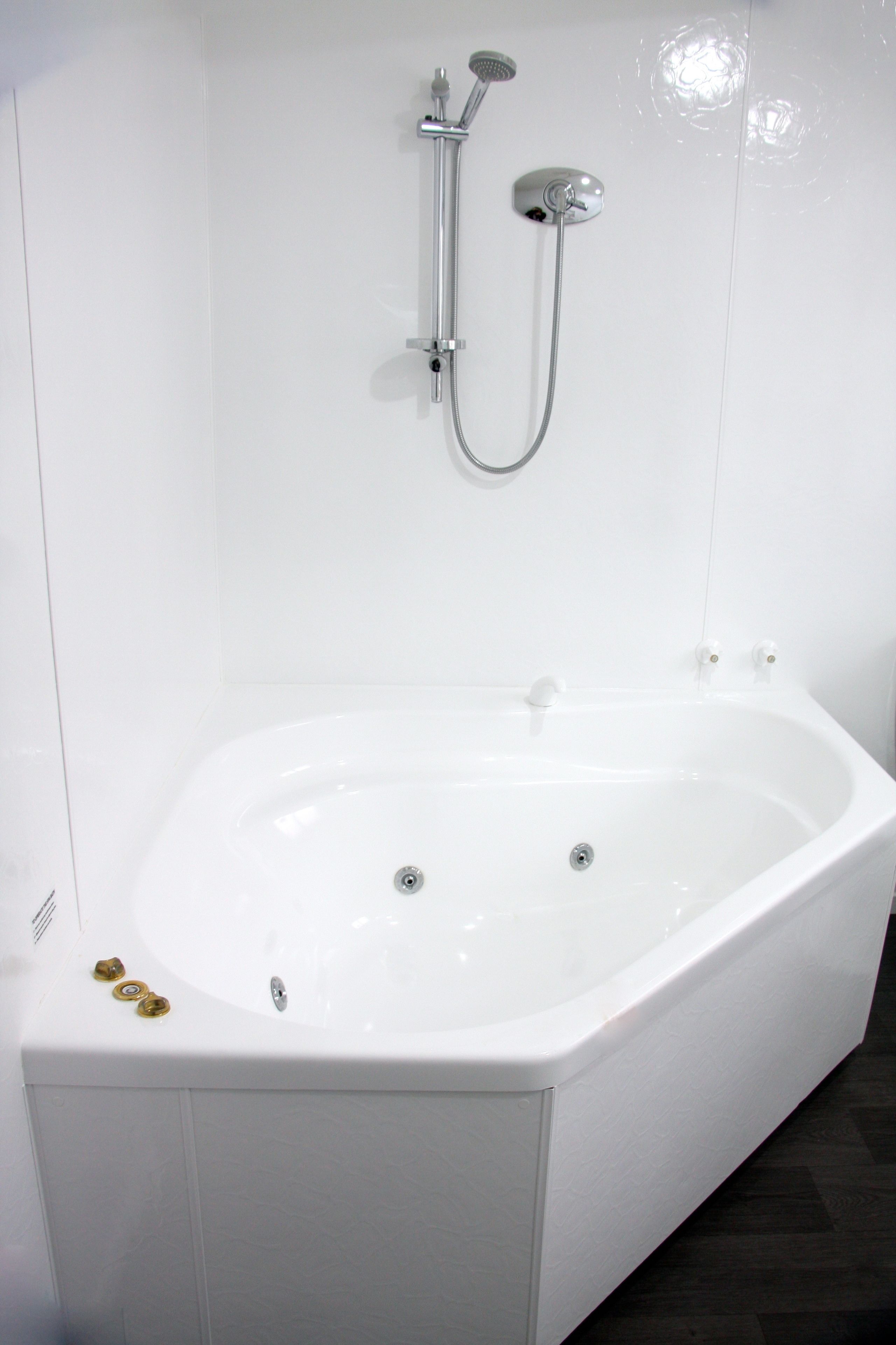 Una bañera blanca con ducha y mandos.