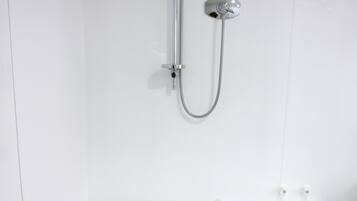 Una bañera blanca con ducha y mandos.