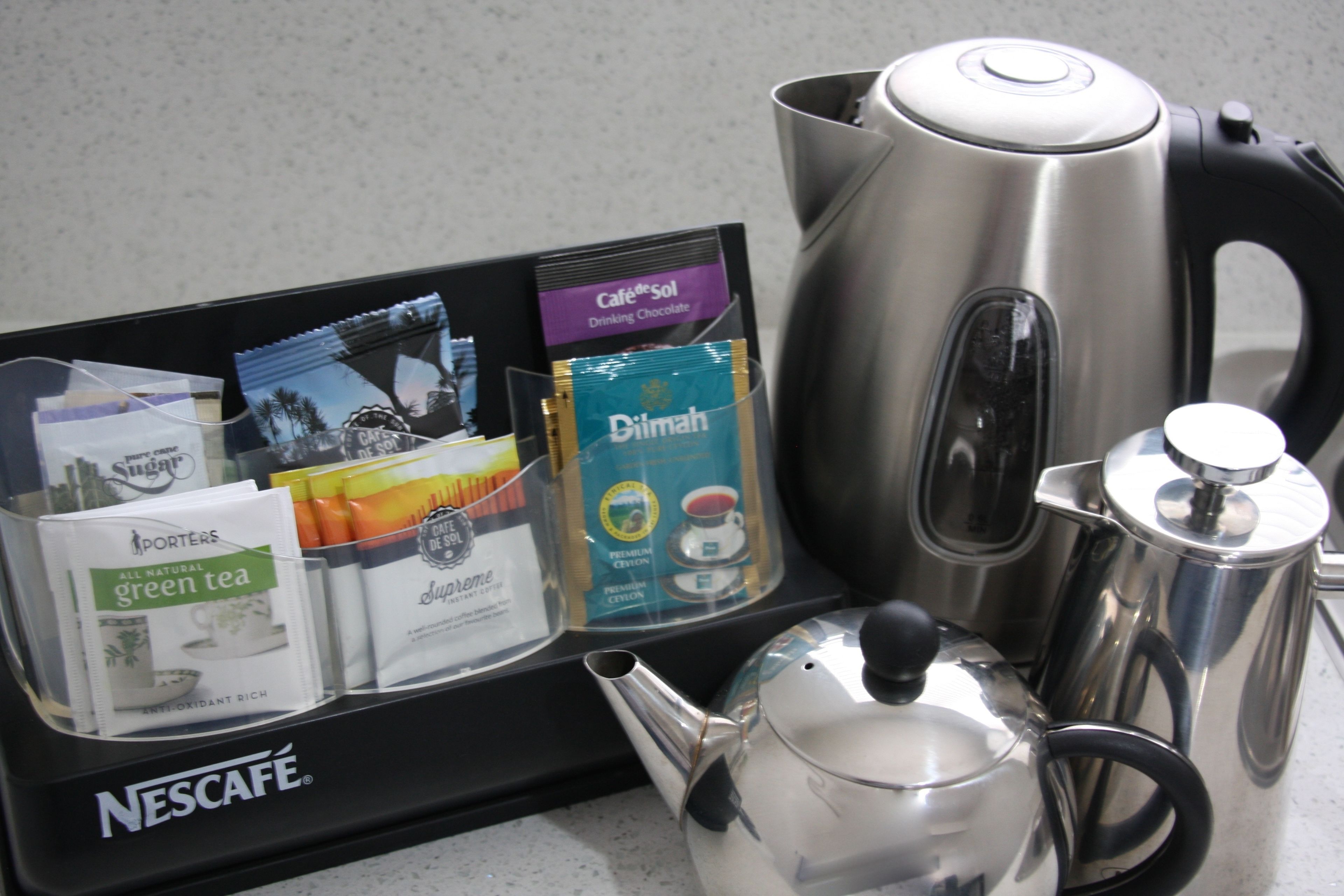 A Nescafé coffee maker, a tea infuser, and various coffee and tea packets on a countertop.