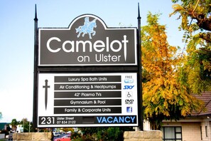 Señal de Camelot en Ulster que enumera comodidades como lujosas unidades de spa, aire acondicionado, televisores de plasma de 42 pulgadas, un gimnasio y piscina, además de unidades para familias y empresas.