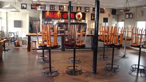 A bar area with multiple wooden bar stools and a bar counter. - Grand Hotel, Whangarei (Whangarei)