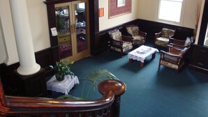 A lobby with a Grand Thai restaurant sign, a staircase, and a seating area with floral-patterned chairs. - Grand Hotel, Whangarei (Whangarei)