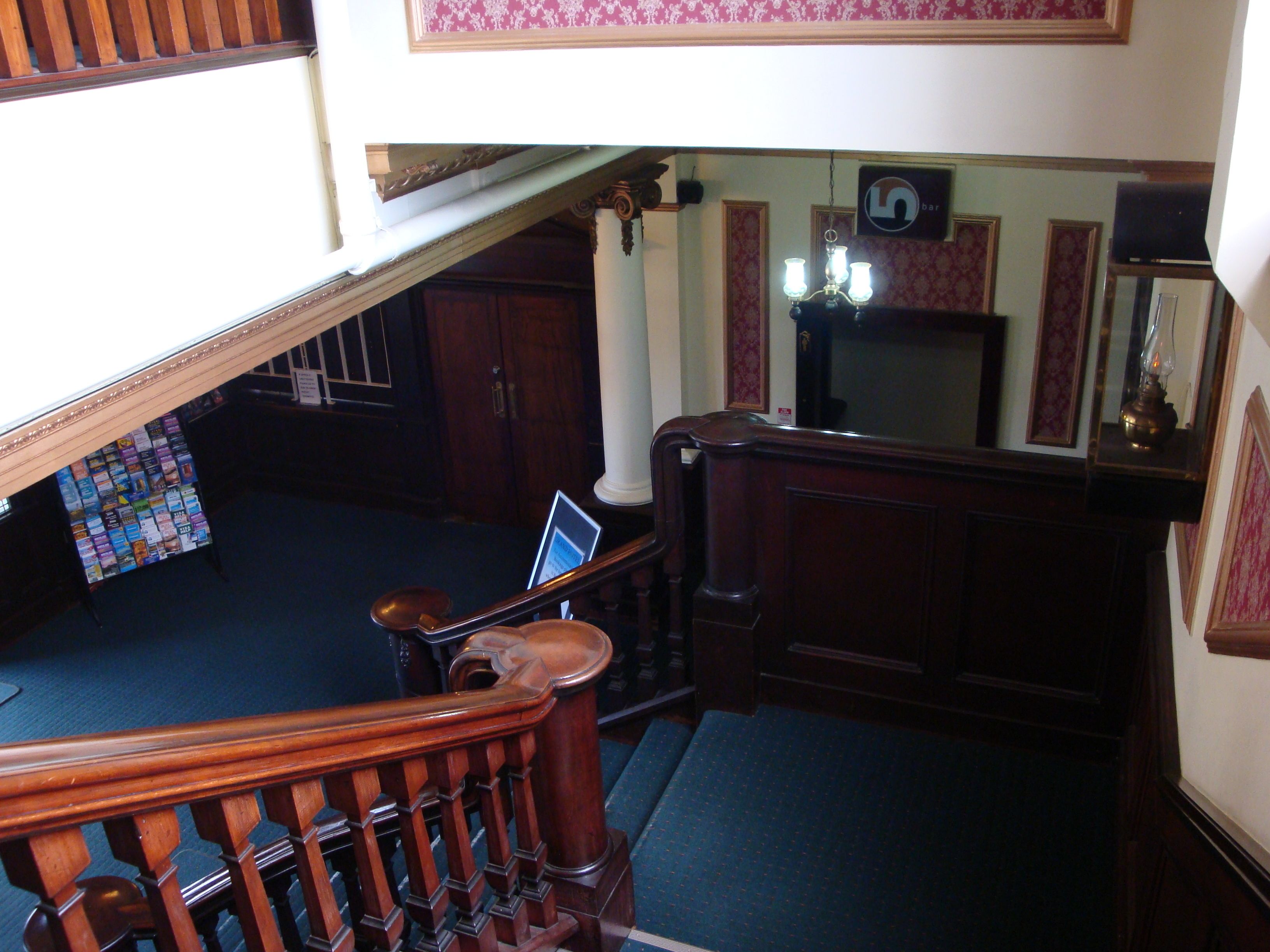 A staircase with a wooden handrail and a blue carpeted landing area.
