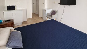 A bedroom with a bed, a desk, a chair, a television, and a ceiling fan. - A1 Inn the City (Cairns)